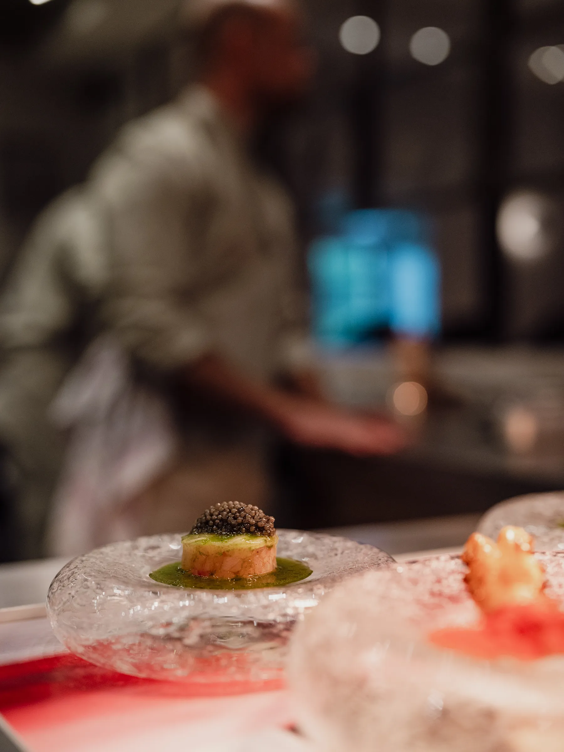 Caviar amuse on glass plate in GEM. kitchen pass during service